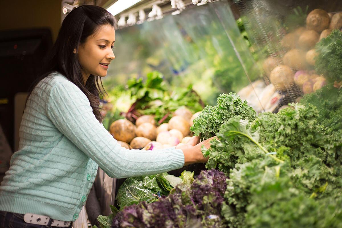 choosing green leafy vegetables in grocery store